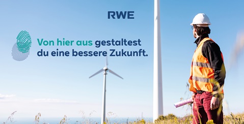 A worker in an orange safety vest stands in front of a wind turbine, gazing at the landscape.