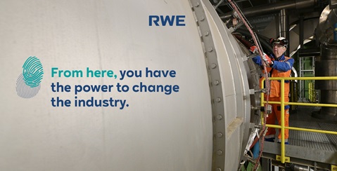 An industrial worker in an orange jumpsuit interacts with a large machine, emphasizing the power to change the industry.