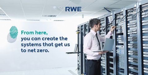 A man in a pink shirt uses a laptop while working on server racks in a modern office environment, promoting net-zero systems.
