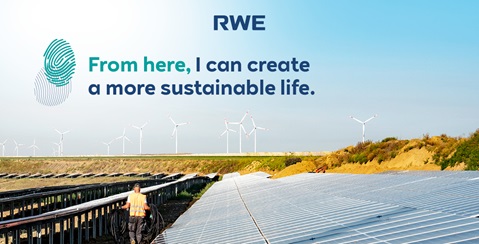 A worker in an orange vest stands on a solar field with wind turbines in the background. Sustainability is emphasised.