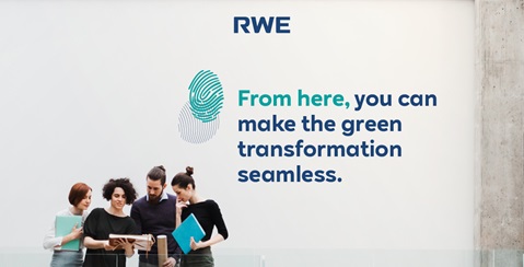 Eine Gruppe von Menschen steht zusammen mit verschiedenen Dokumenten vor einer Wand mit dem RWE-Logo und einer Botschaft zur grünen Transformation.