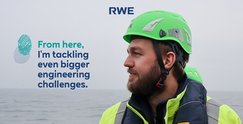 An engineer wearing a green helmet stands before a grey sea, ready to tackle significant challenges.