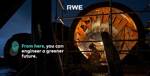 A worker in an orange suit operates inside a large, cylindrical machine, with soft lighting illuminating the dark surroundings.