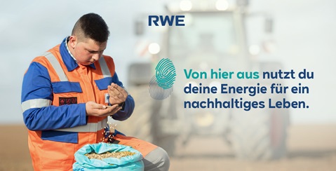 Ein Landwirt in orange-blauer Arbeitskleidung hält eine Handvoll Getreide, während ein Traktor im Hintergrund sichtbar ist.