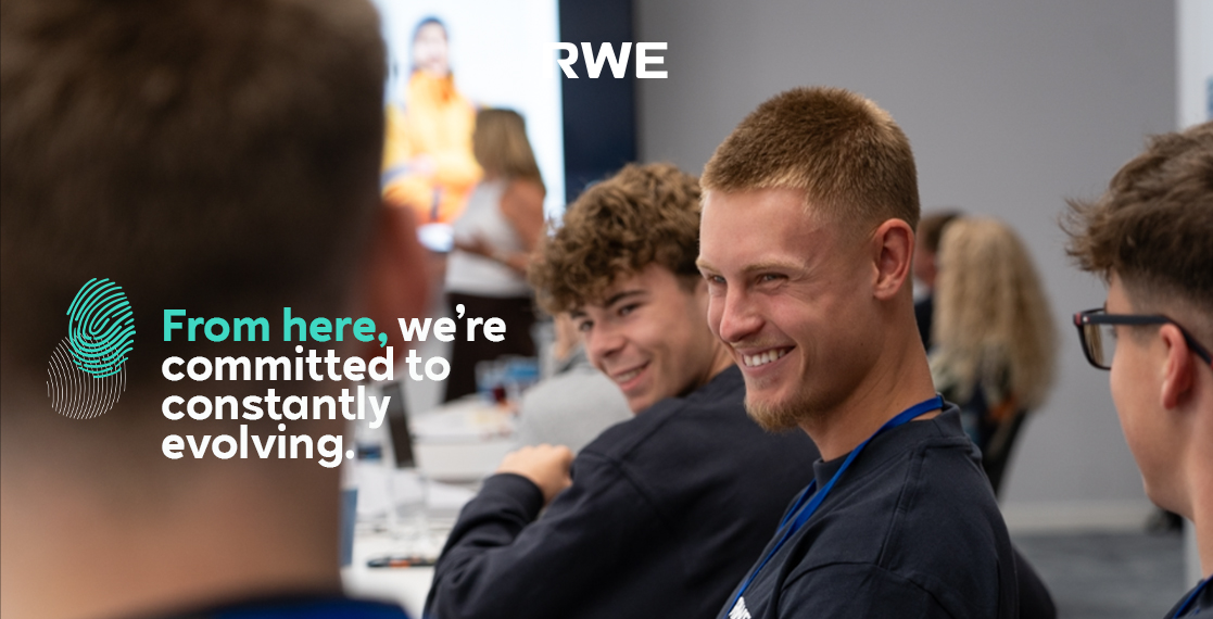 A group of young people in a meeting. In the centre, the slogan reads: 'From here, we’re committed to constantly evolving.