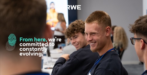 A group of young people in a meeting. In the centre, the slogan reads: 'From here, we’re committed to constantly evolving.