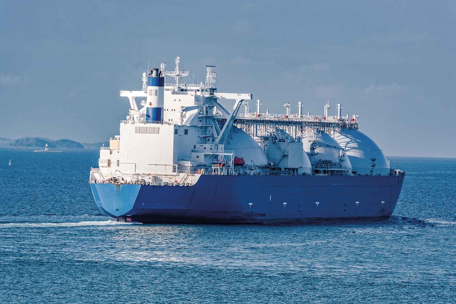 Ein großes LNG-Tankschiff fährt durch ruhige Gewässer mit einem blauen Rumpf und einer weißen Überbaukonstruktion im Hintergrund.