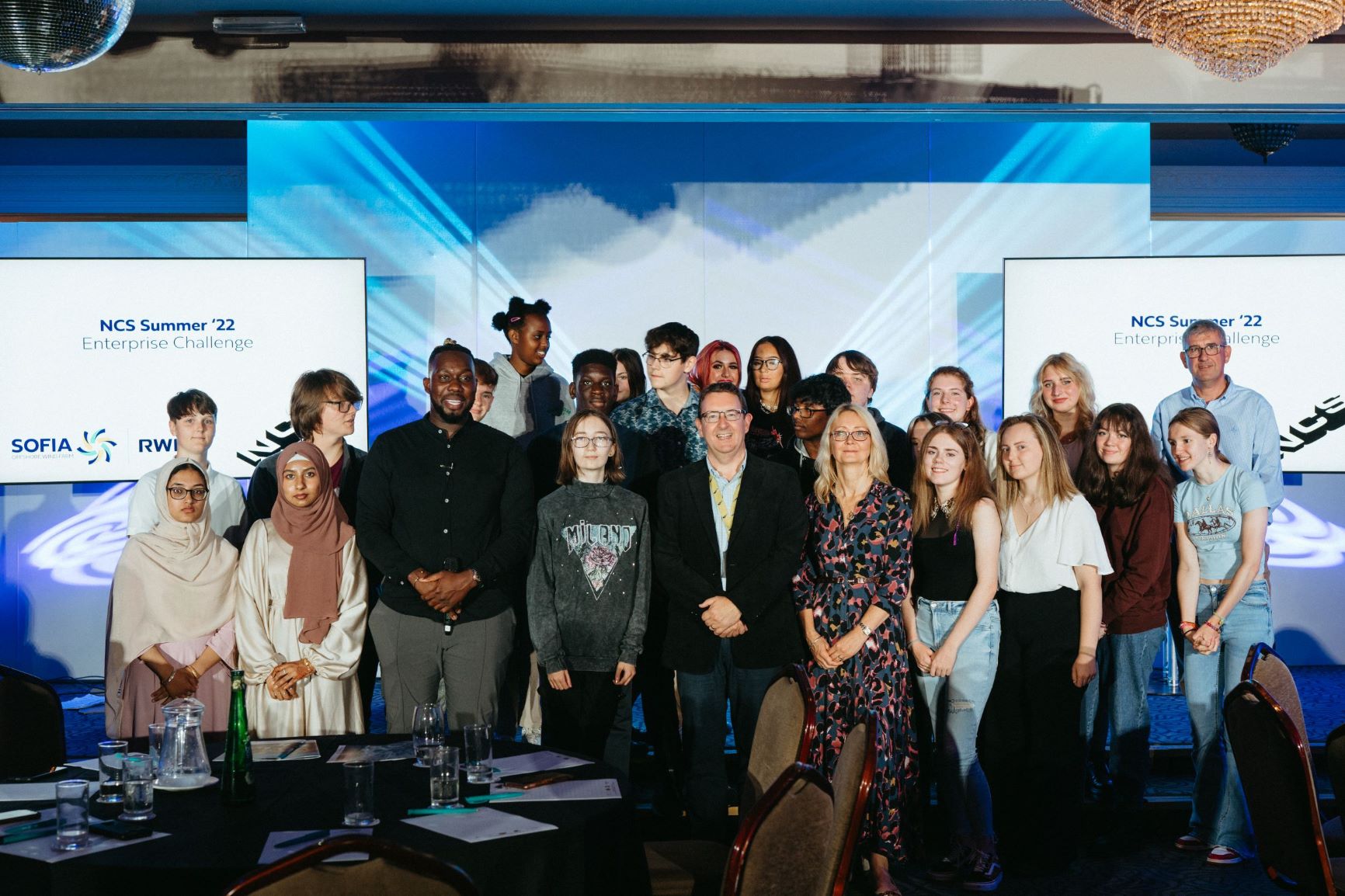 Group of participants at the NCS Summer '22 Enterprise Challenge event, smiling together in a well-lit room.
