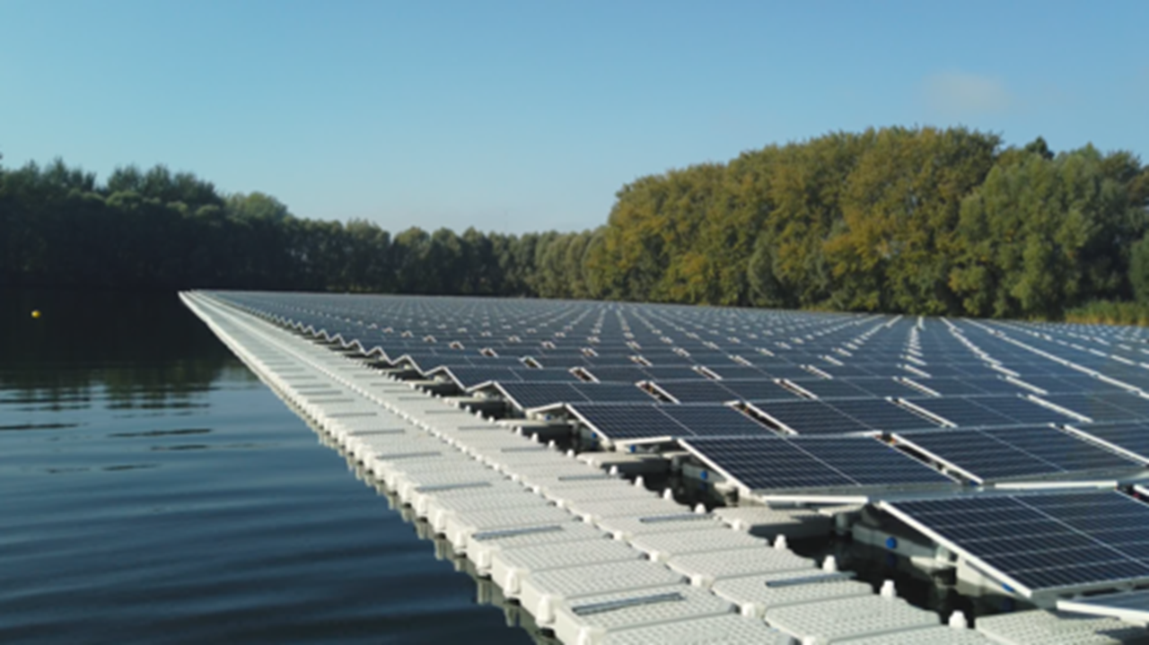 Eine schwimmende Solaranlage auf einem ruhigen Wasser mit Bäumen im Hintergrund.