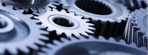Close-up of several metallic gears of varying sizes and shapes on a dark background.