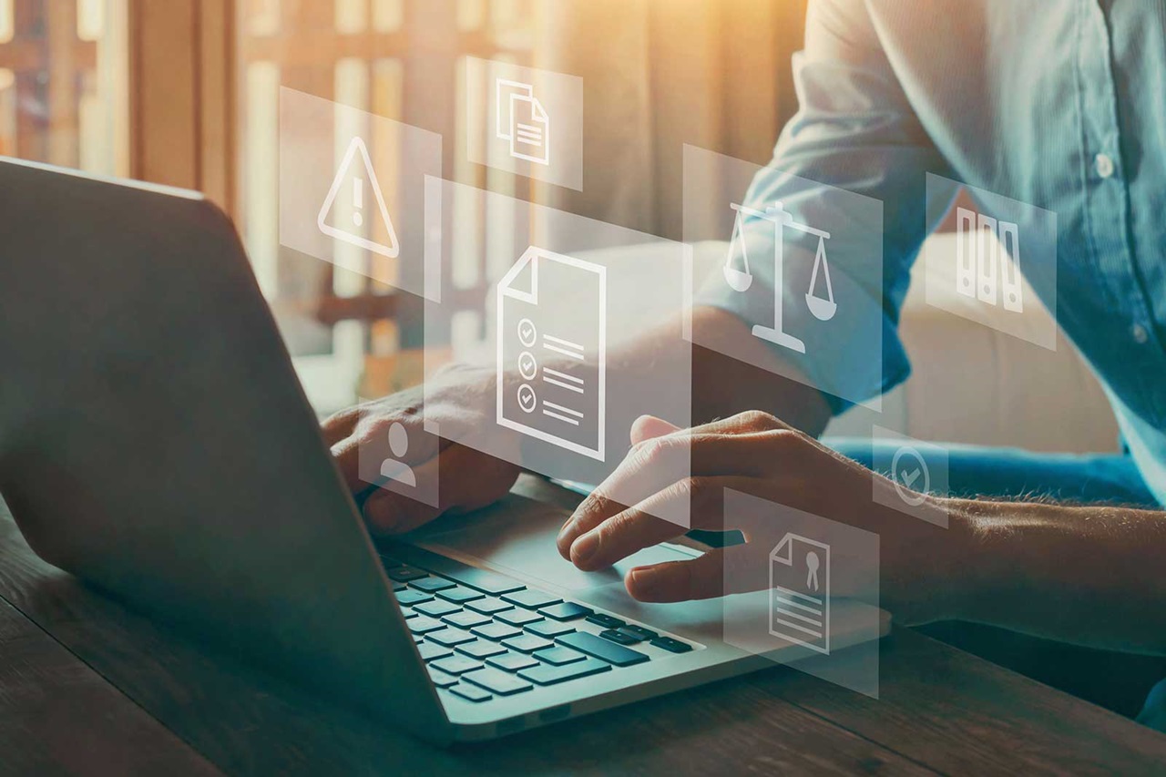 A person works on a laptop, surrounded by digital icons for documents, warnings, and legal symbols.