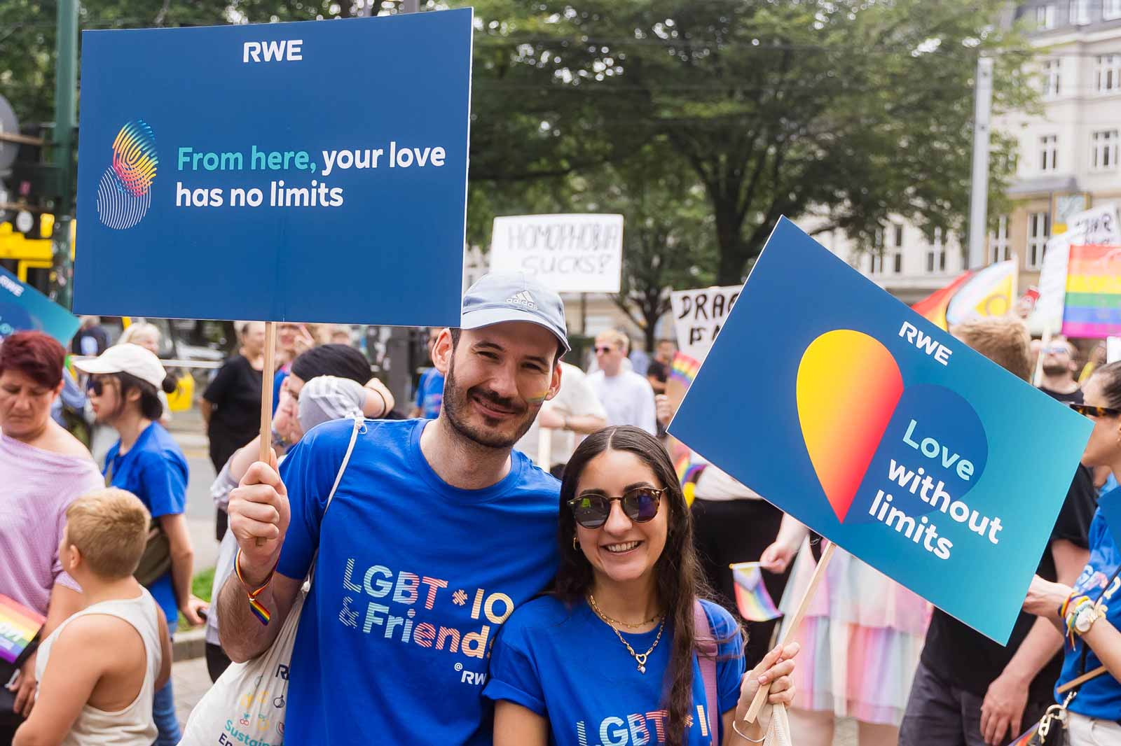Participants hold colourful signs at a parade. One sign reads: 'From here, your love has no limits'.