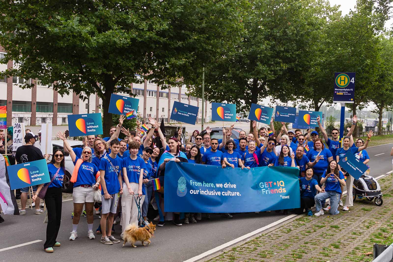 Participants hold colourful signs at a parade. One sign reads: 'From here, your love has no limits'.