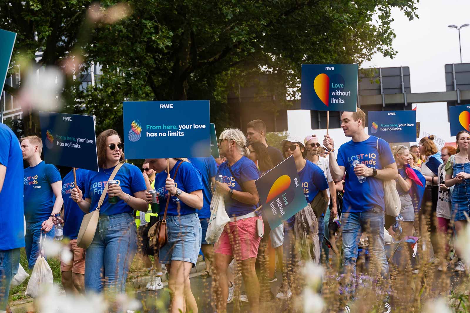 Participants hold colourful signs at a parade. One sign reads: 'From here, your love has no limits'.