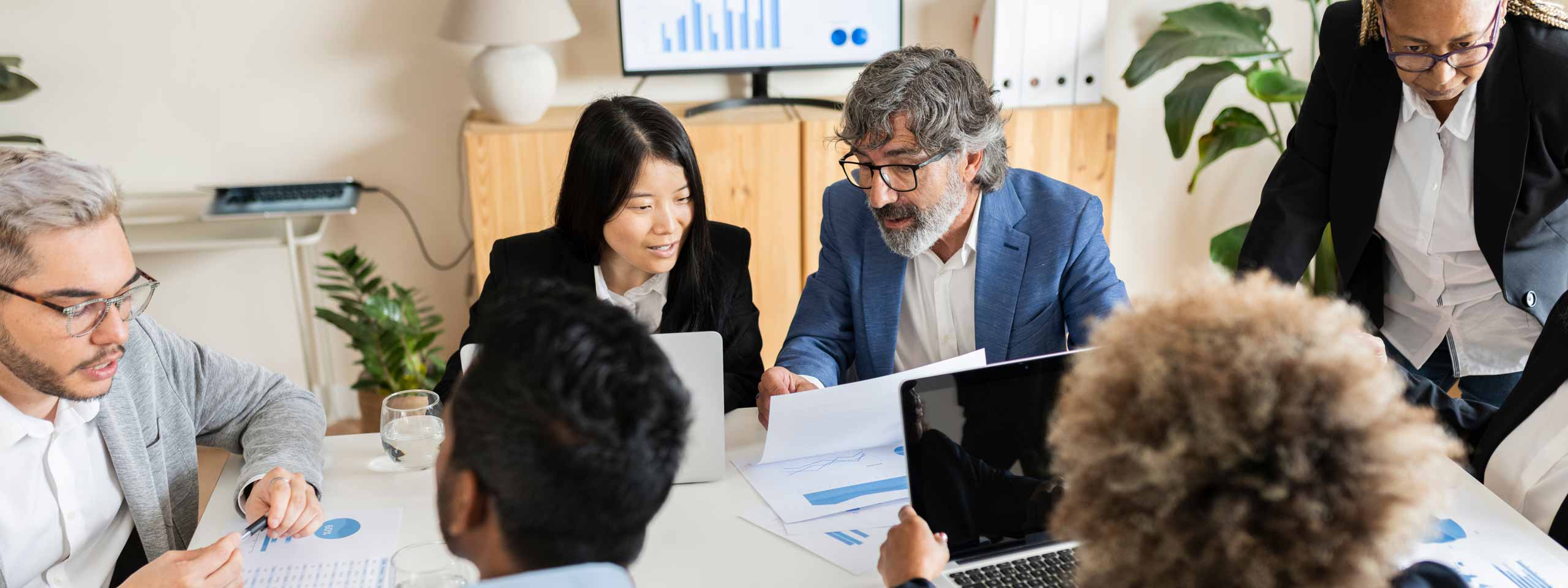 A group of people in a meeting room discussing charts and presentations.