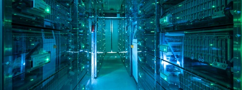 An illuminated corridor of server racks with blue and green lights in a data centre.