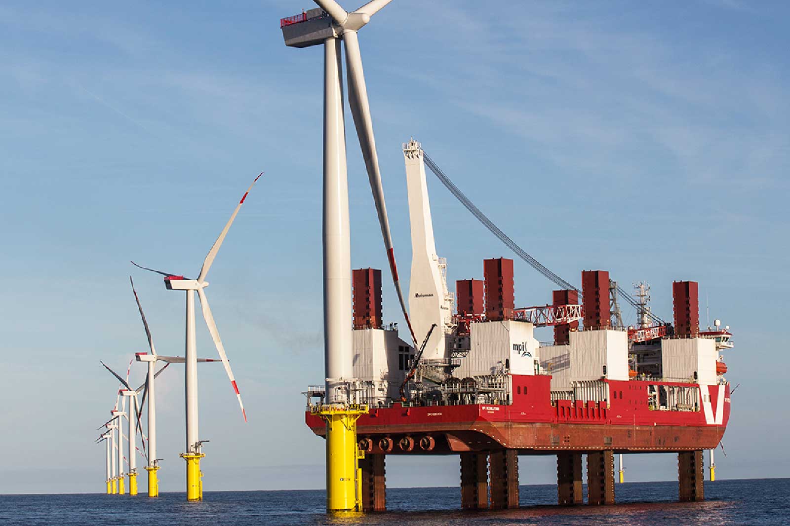Ein Offshore-Windpark mit mehreren Windturbinen und einem Spezialschiff zur Installation auf dem offenen Wasser.