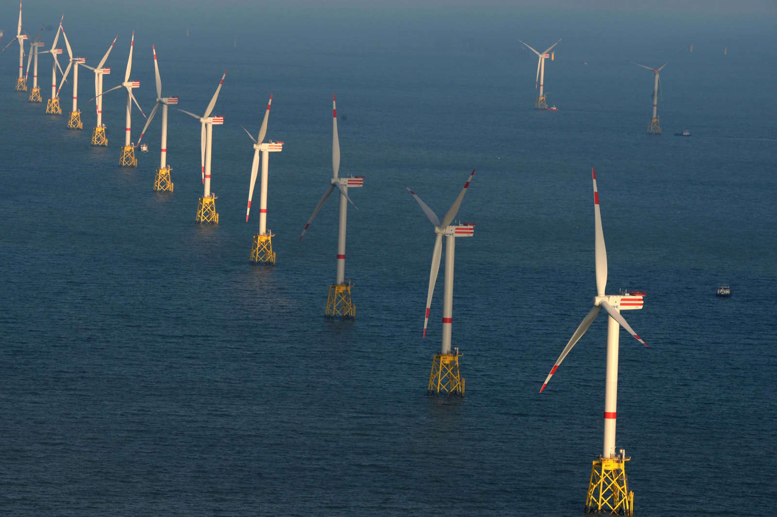 Eine Reihe von Windkraftanlagen auf dem Meer, die in einem klaren Wetterbild zu sehen sind.