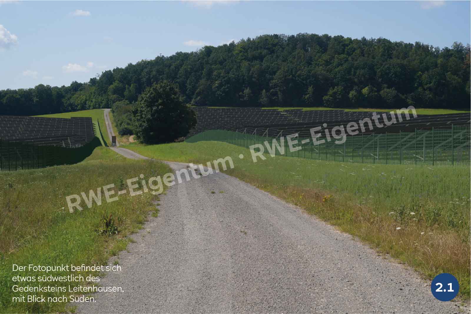 Ein Kiesweg verläuft zwischen grünen Feldern mit Solarpanelen links und Bäumen im Hintergrund, mit Blick nach Süden.