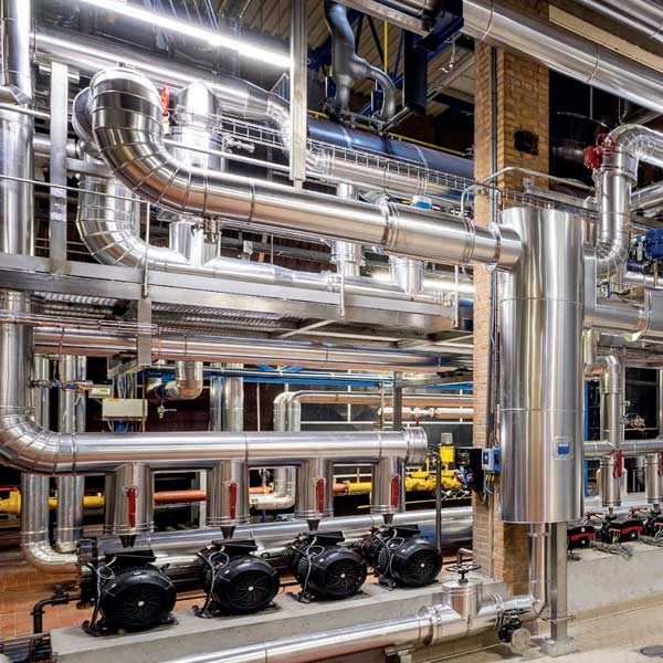 An industrial piping system with shiny silver pipes and several motors in a functional environment.