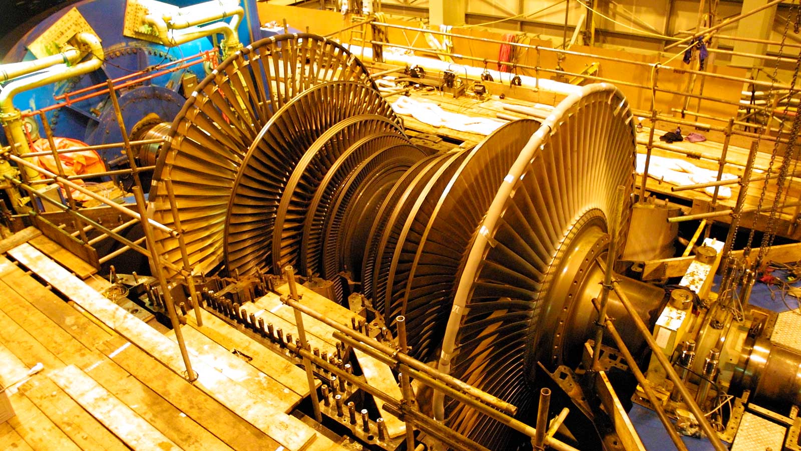 A large turbine with many blades, surrounded by scaffolding in an industrial setting.