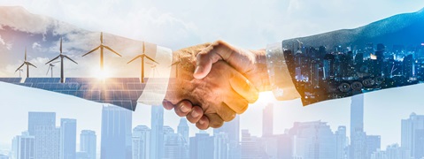 Zwei Hände schütteln sich mit Windkraftanlagen und einer Stadtansicht im Hintergrund, symbolisiert Zusammenarbeit und Nachhaltigkeit.