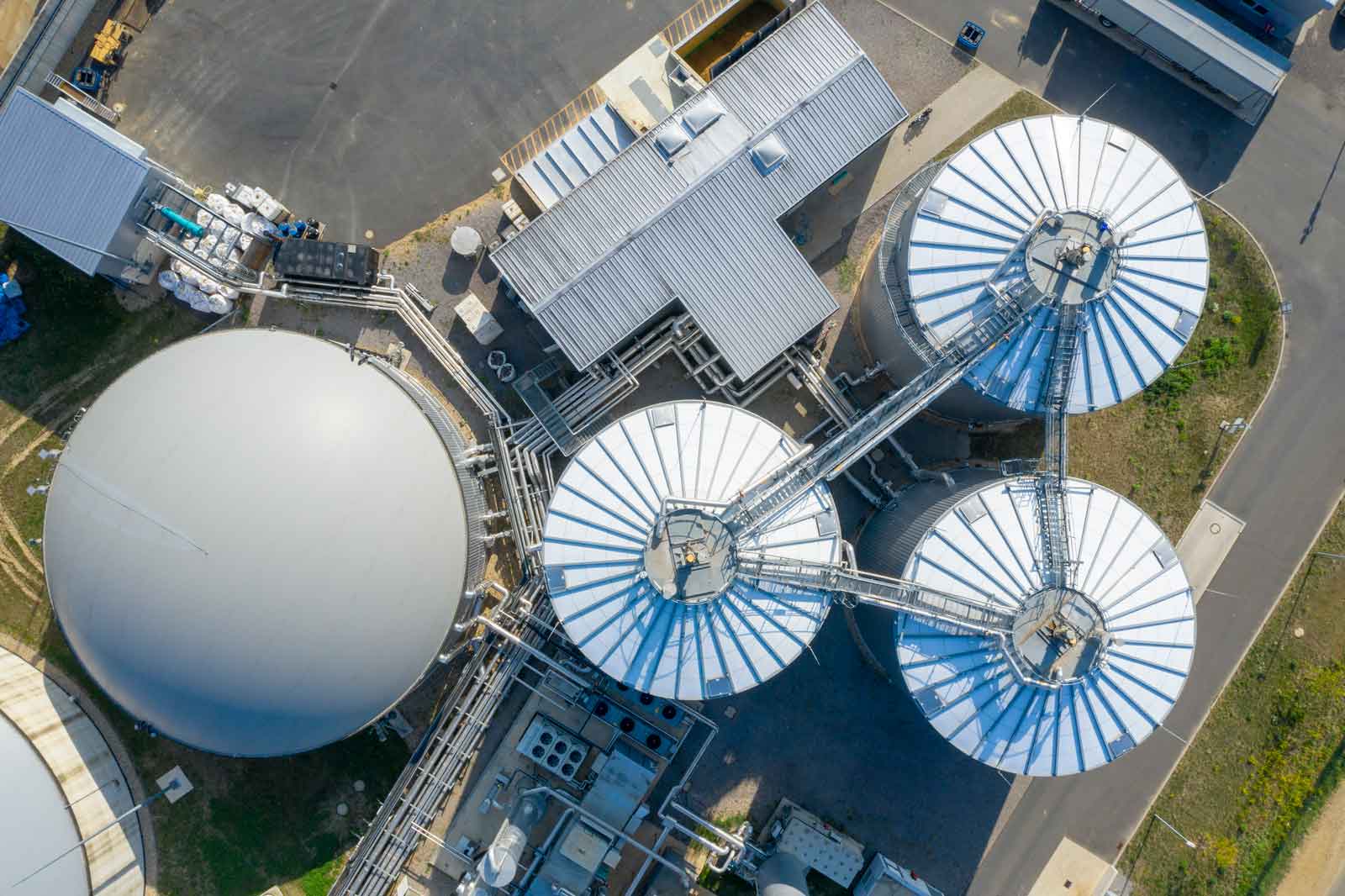 Aerial view of an industrial site featuring large silos, piping, and storage buildings.