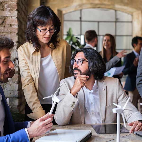 Eine Gruppe von Menschen in einem modernen Büro, die an einem Tisch mit Windturbinenmodellen diskutieren.