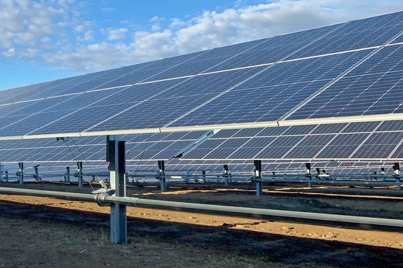 A solar farm featuring multiple solar panels installed on a gravel surface.