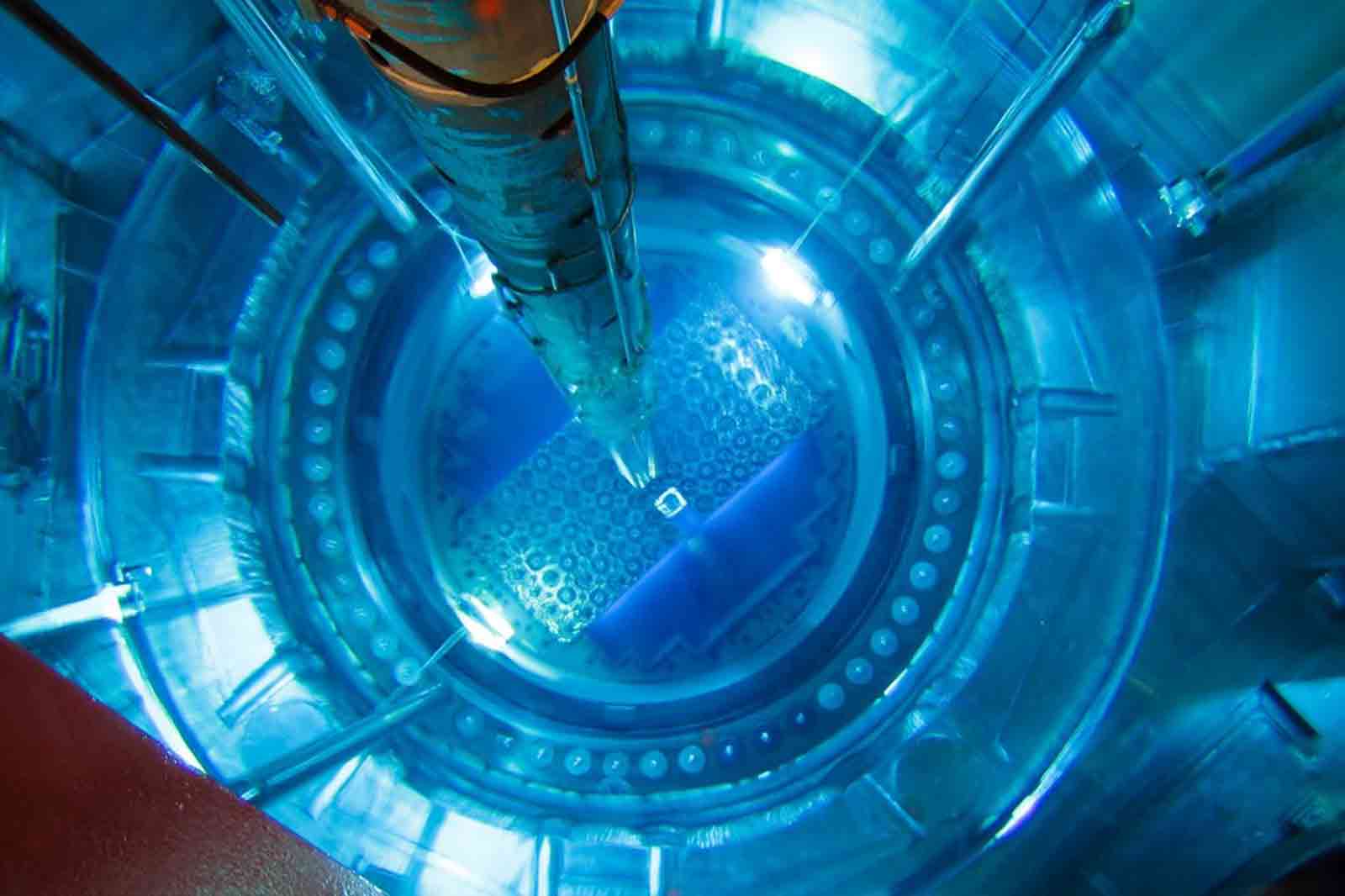 Eine Draufsicht auf den Kern eines Kernreaktors mit blauer Beleuchtung, die die Brennstäbe und hexagonalen Anordnungen zeigt.