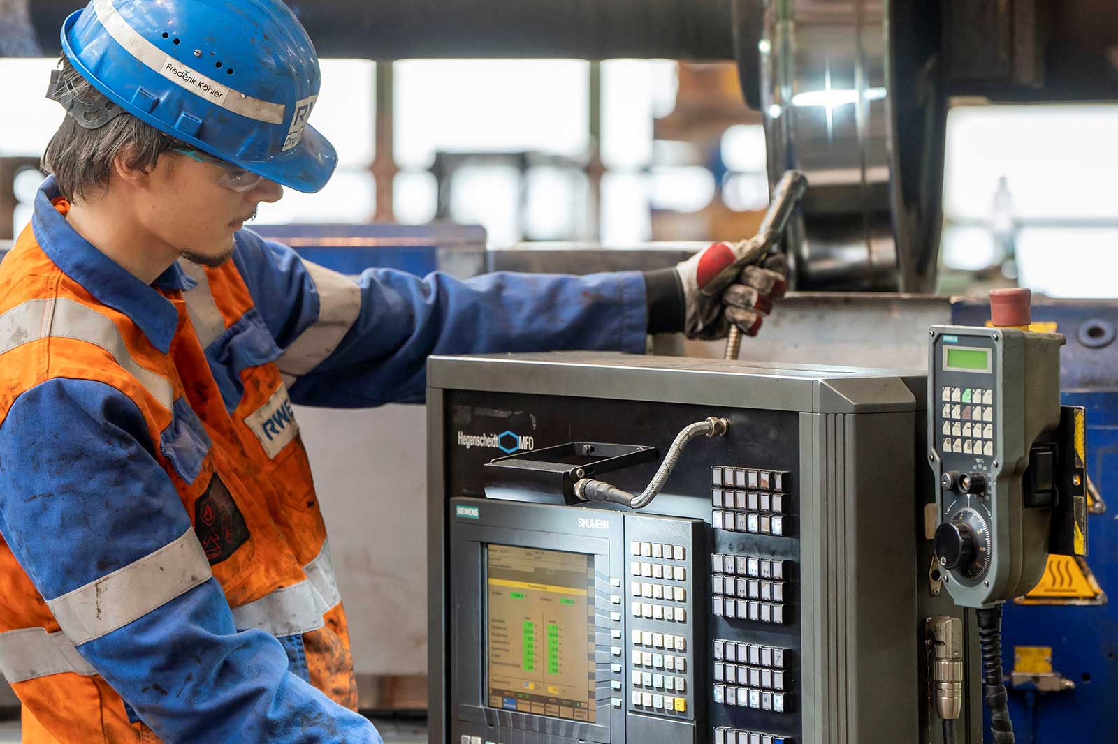 Ein Arbeiter bedient ein Bedienfeld für Industriegeräte in einer Werkstatt.