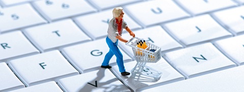 Eine kleine Figur mit einem Einkaufswagen auf einer Tastatur, umgeben von weißen Tasten.