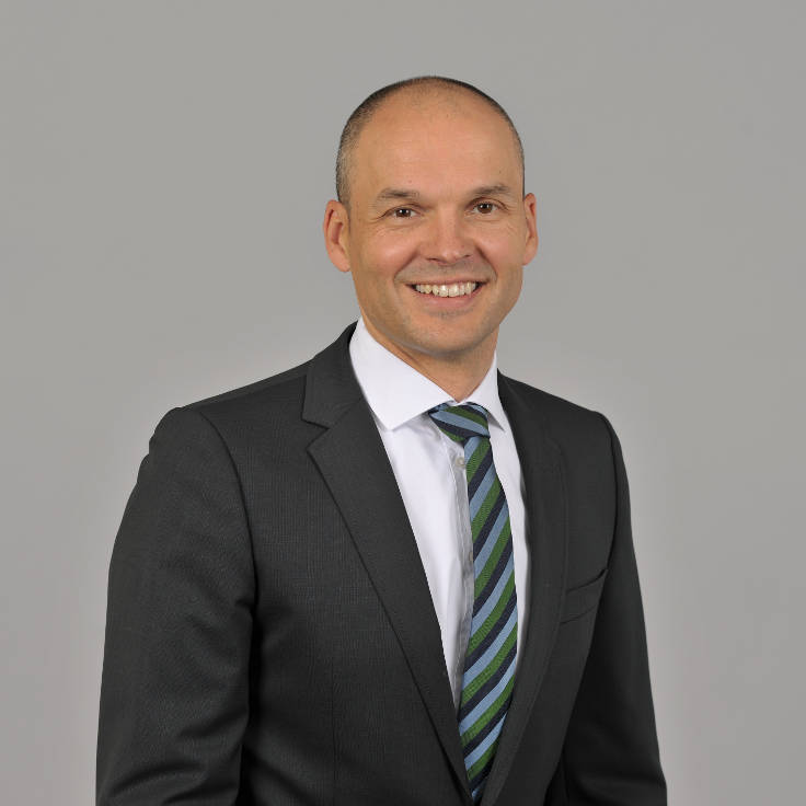 A man in a suit wearing a striped tie against a grey background, portrait of Paulo Sousa Lopes.