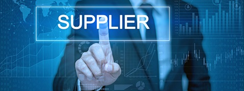 A businessman pointing at the word 'SUPPLIER' on a digital interface with graphs and data visualisations in the background.