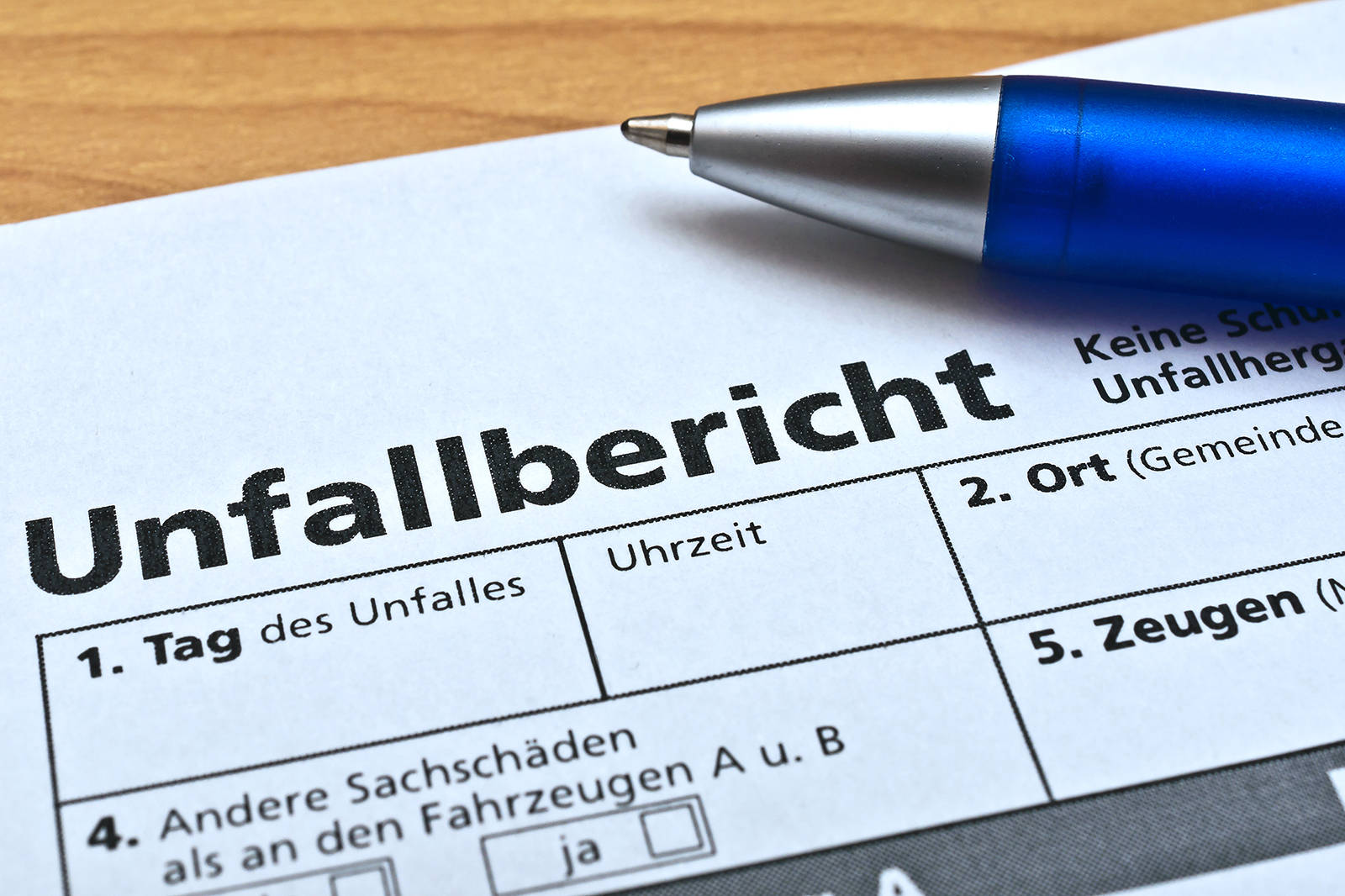 Ein Unfallbericht mit Feldern für Datum, Uhrzeit, Ort und Zeugenaussagen liegt auf einem Tisch.