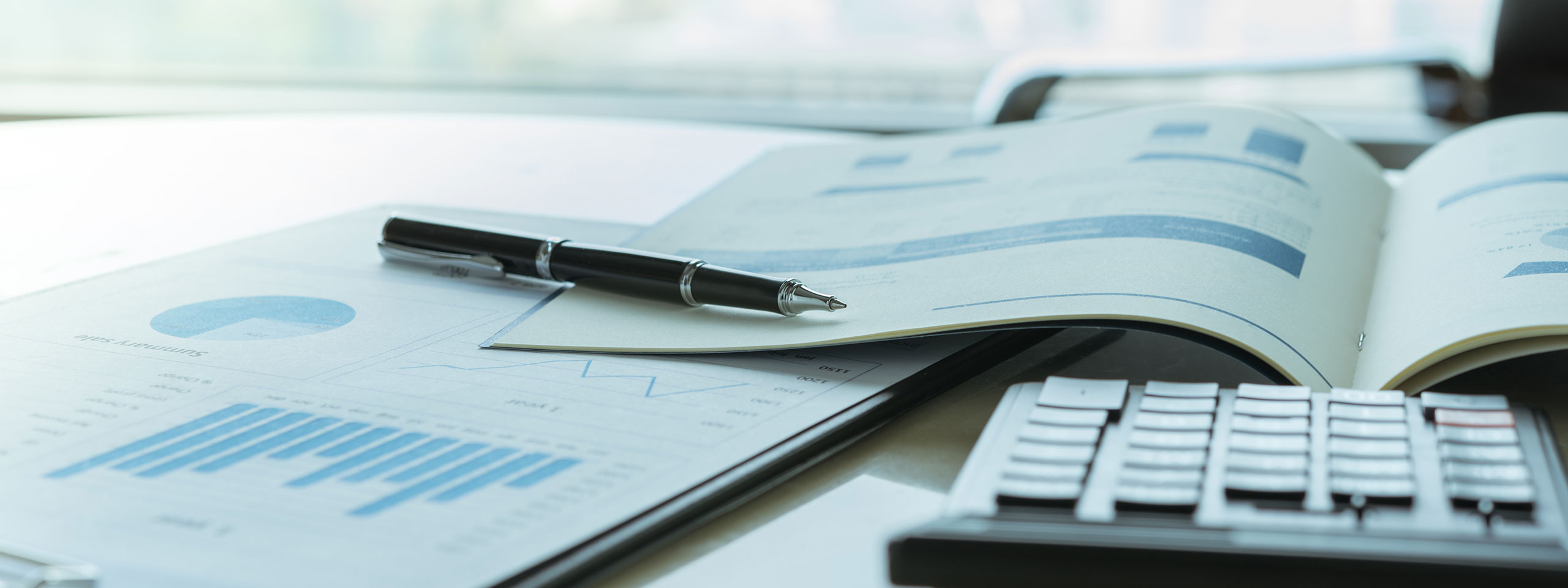 Ein Tisch mit Graphen, Diagrammen und einem Kugelschreiber. Ein Taschenrechner liegt daneben.