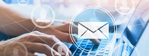 Die Hände einer Person, die auf einem Laptop tippen, mit überlagerten E-Mail- und Benutzer-Icons in sanfter Fokussierung.