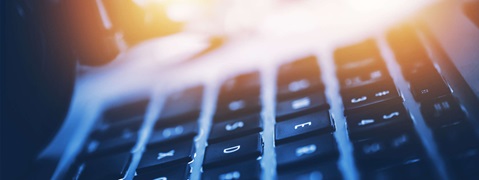Close-up of a keyboard with soft lighting, visible keys, in a gentle blue-orange hue.