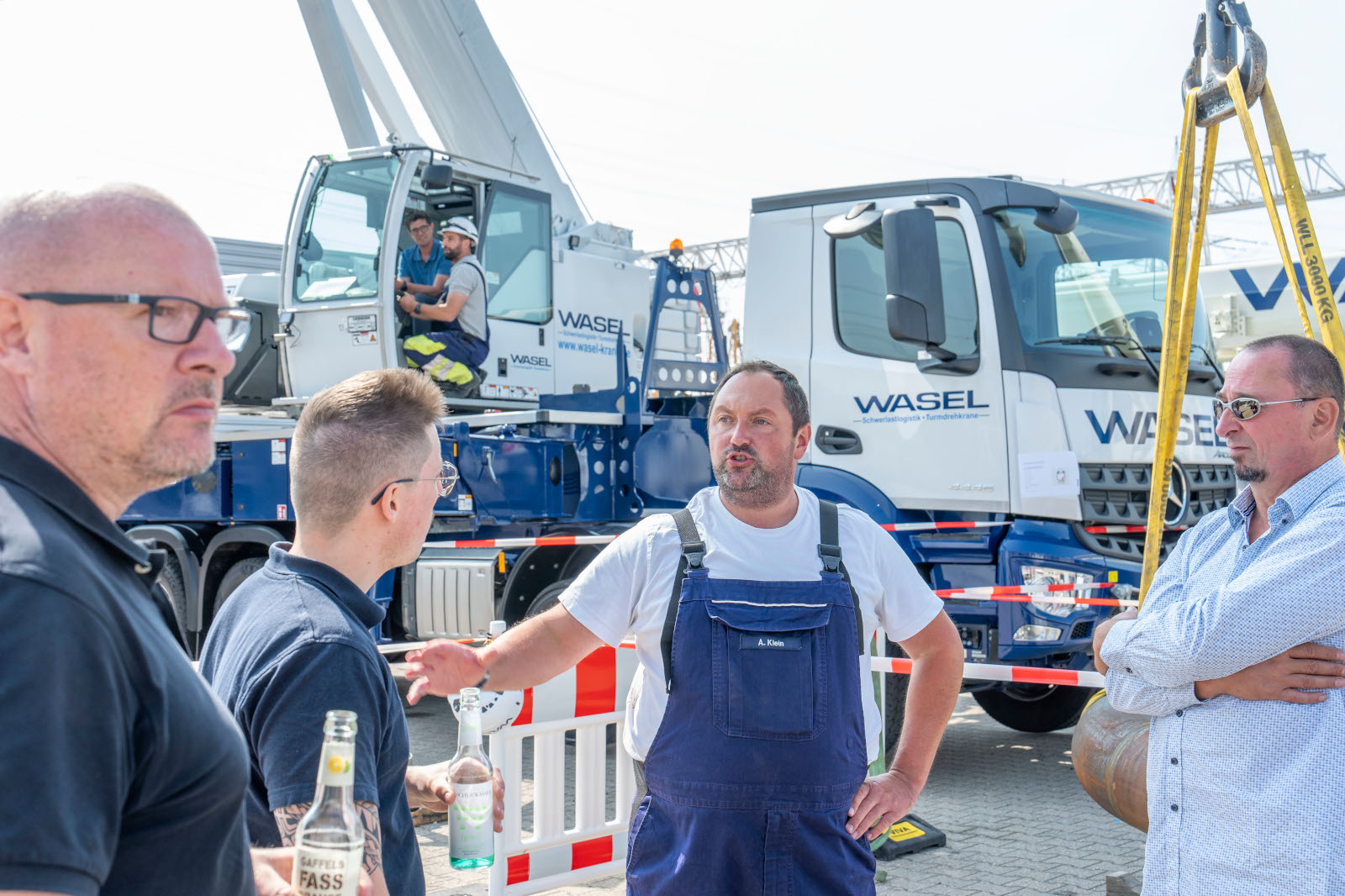 Eine Gruppe von Arbeitern diskutiert neben einem Lkw mit einem Kran in einem Baustellenbereich.