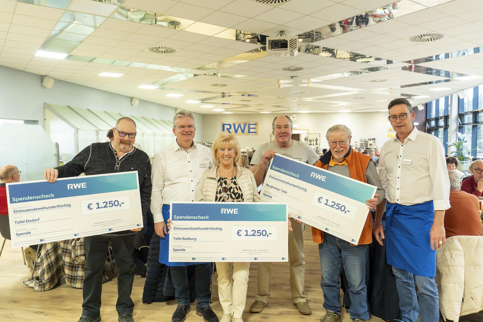 Eine Gruppe von sechs Personen hält große Spendenchecks in einem gut beleuchteten Raum mit RWE-Branding.