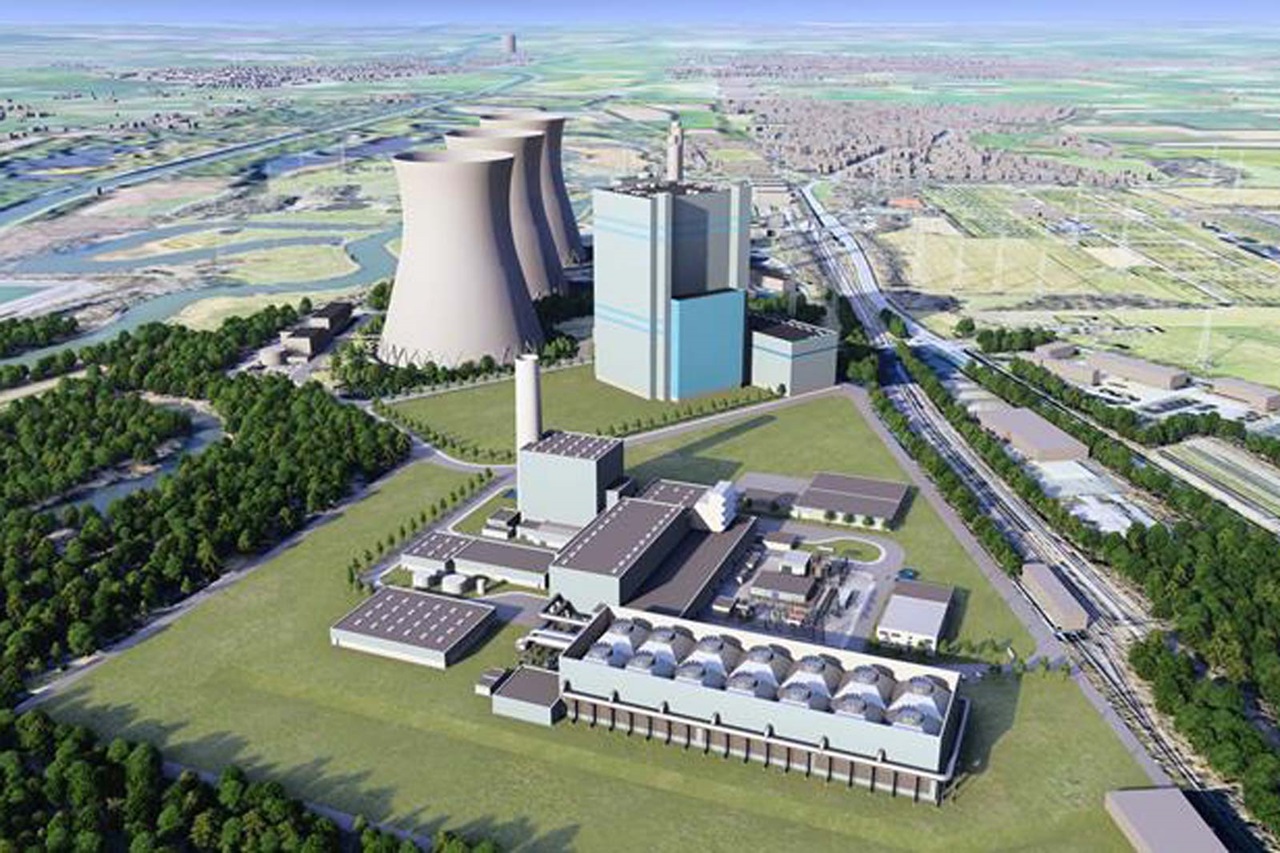 Luftaufnahme eines Kraftwerks mit Kühltürmen, verschiedenen Industriegebäuden sowie umgebendem Grün und Wasserflächen.