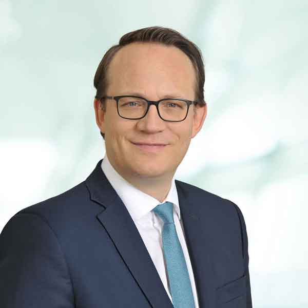 Ein Geschäftsmann in einem Anzug mit einer Krawatte posiert vor einem unscharfen Hintergrund, Portrait von Dr. Markus Krebber.