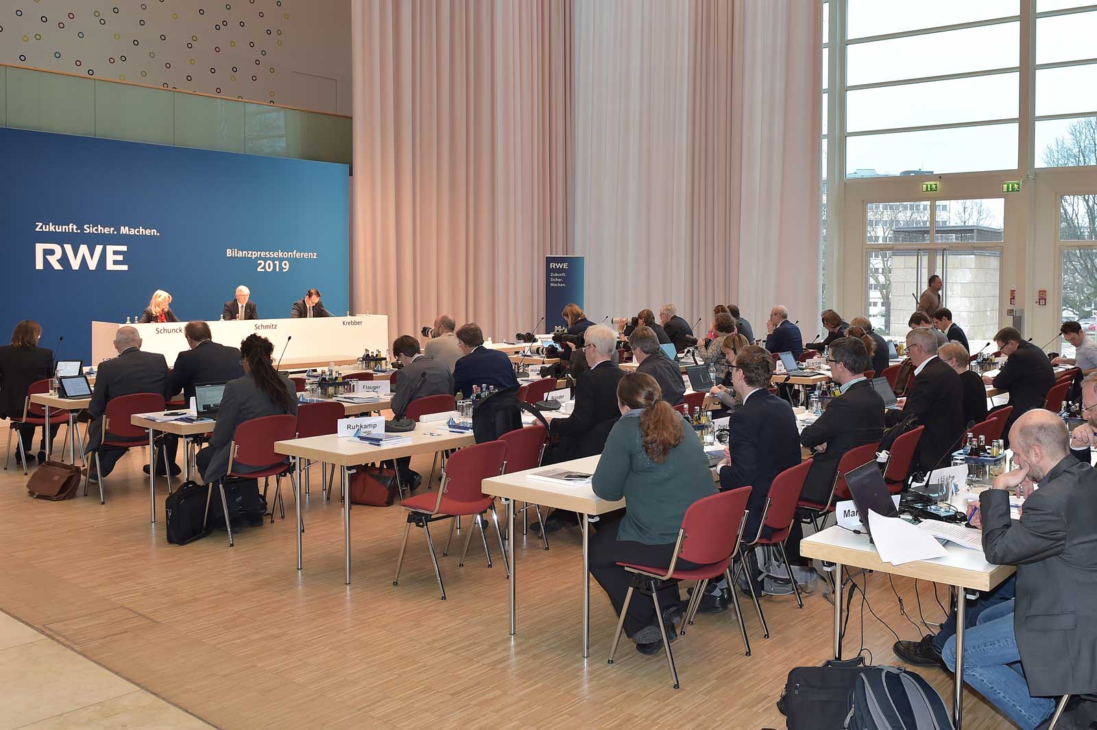Conference room with numerous participants seated around tables at an RWE press conference in 2019.