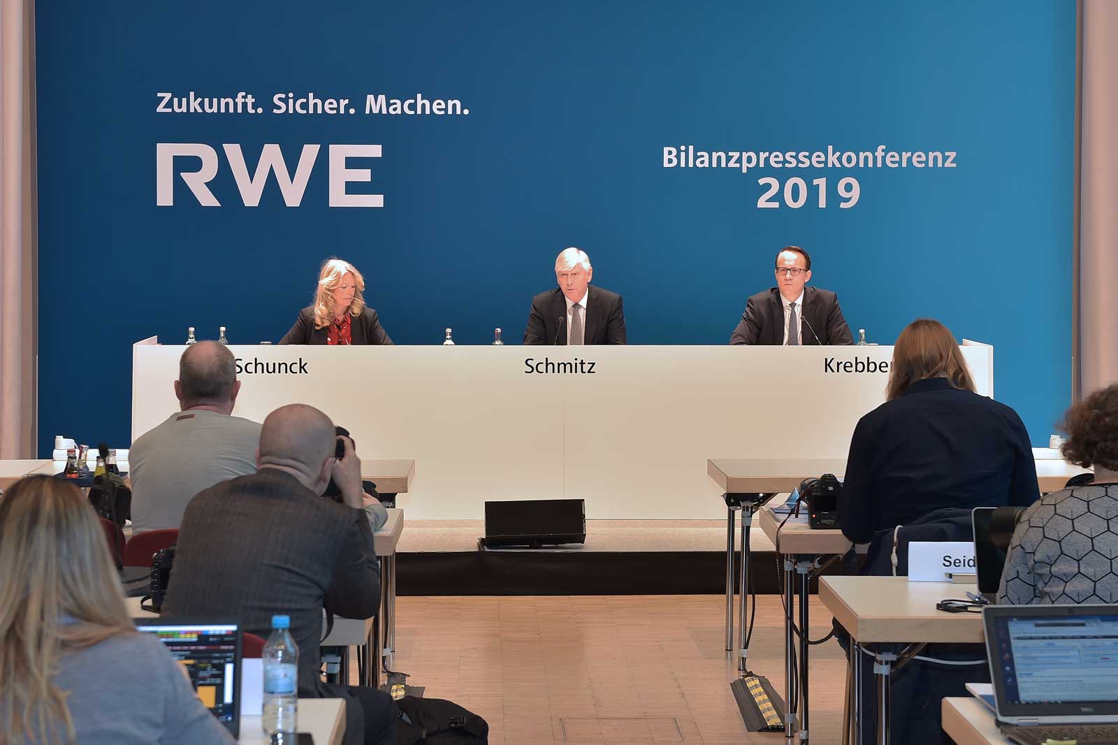 RWE press conference 2019 with speakers at a table against a blue background.