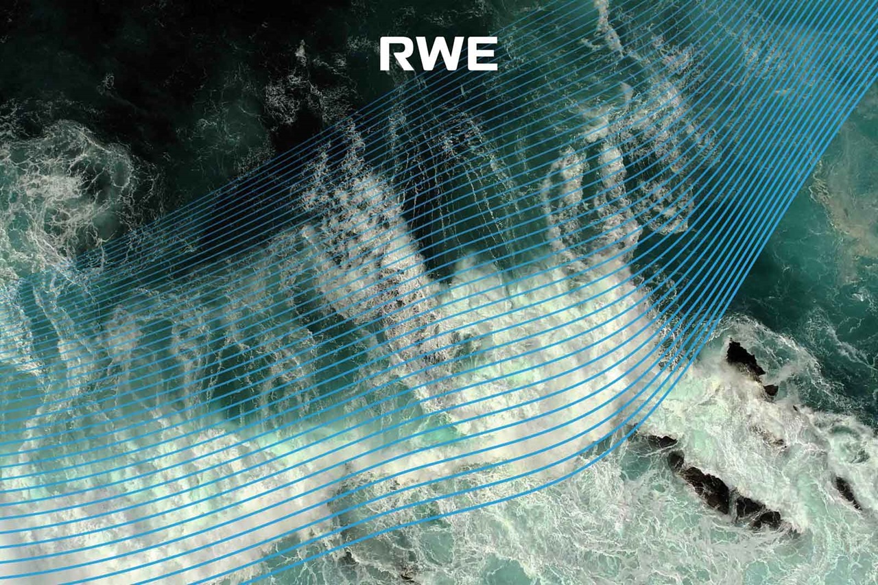 Aerial view of water surface with blue lines indicating movement. Dark rocks and foamy waves are visible in the background.