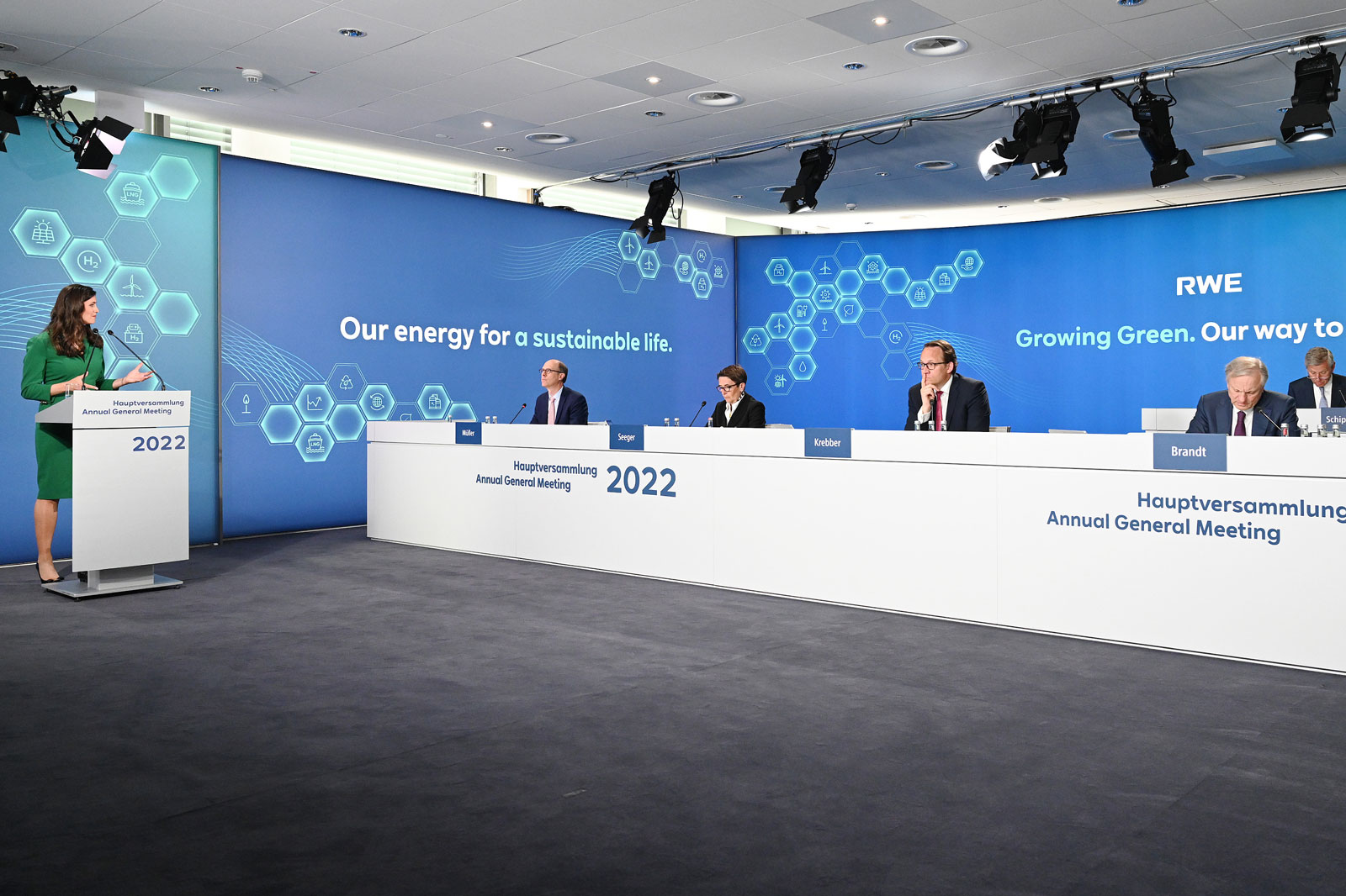 A woman is speaking at the RWE 2022 Annual General Meeting, with several people seated at the table.