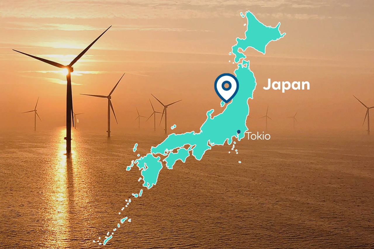 Eine Karte von Japan mit Tokio, umgeben von Windkraftanlagen vor einem orangeroten Sonnenuntergang.