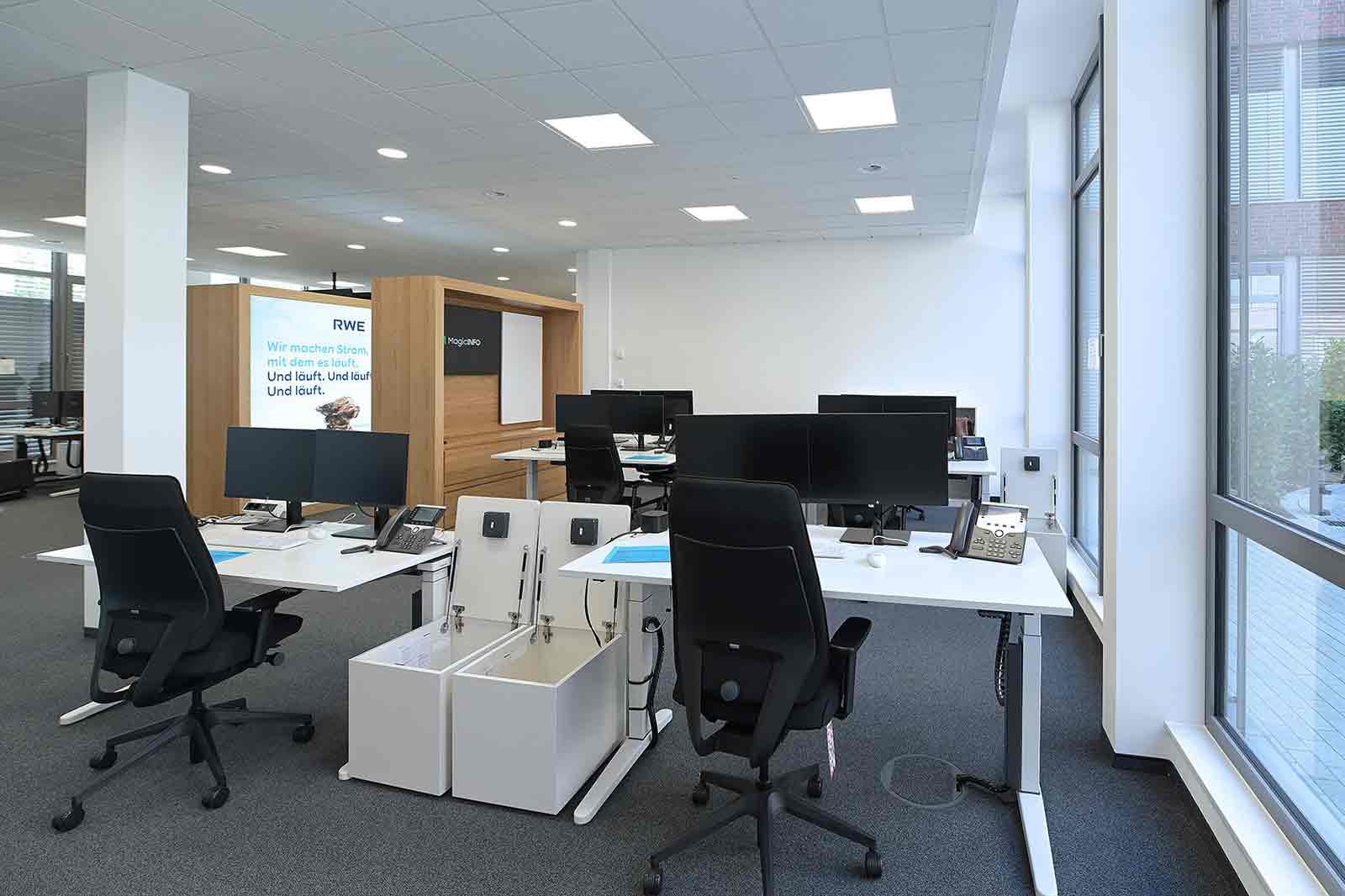 Ein modernes Büro mit mehreren Schreibtischen, Computerbildschirmen und einem ruhigen, professionellen Ambiente.