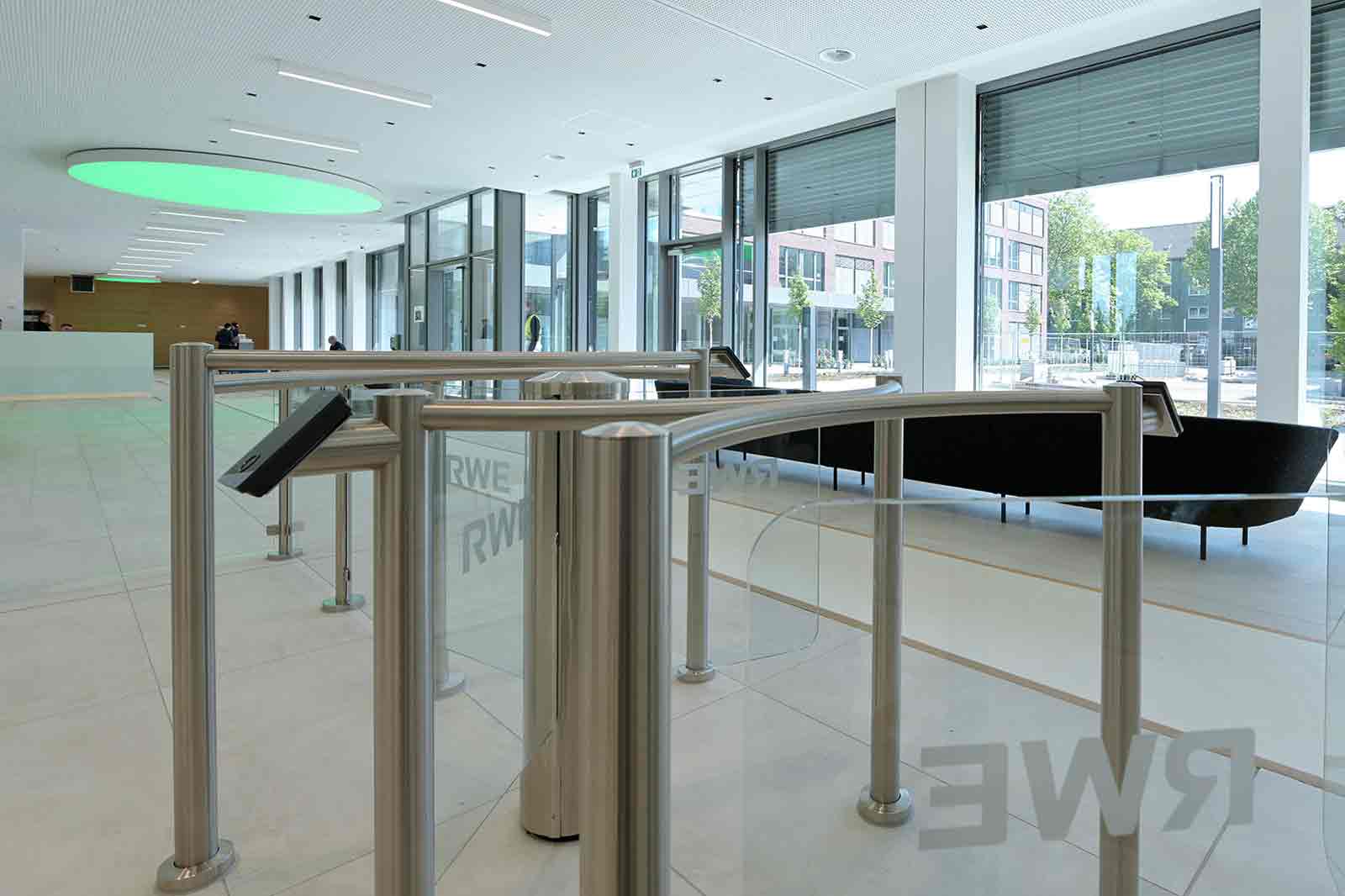 Moderne Eingangsbereich mit automatischen Drehtüren und großen Fenstern, die viel Licht hereinlassen.