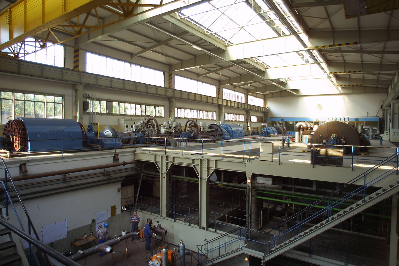 Eine Industrieanlage mit großen Maschinen, einschließlich Generatoren, unter natürlichem Licht von den Fenstern oben.